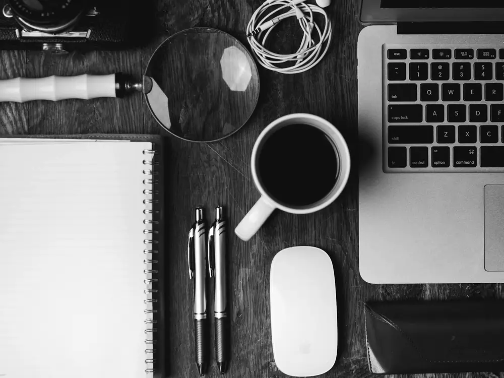 Mesa de trabajo ordenada con cuaderno, teclado y una taza de café vista desde arriba